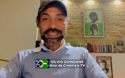 Homem sentado, de pele negra e bone, vestindo camisa azul clara