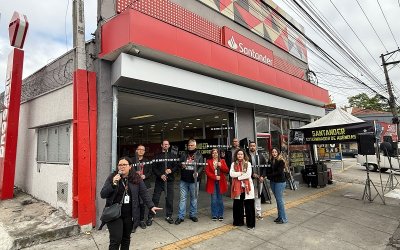 Imagem mostra dirigentes sindicais em frente a uma agência do santander, durante protesto contra o fechamento da unidade, os dirigentes estão de braços cruzados e lado a lado