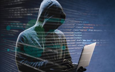 Imagem mostra uma pessoa usando blusa com capuz e um notebook na mão