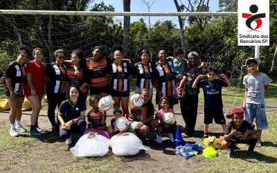 Fotografia do tipo feminino de futebol de várzea, posando em frente à trave, com logo do Sindicato aplicada no canto superior direito da imagem.