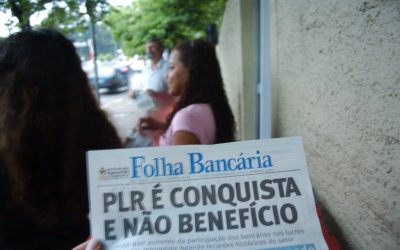 Fotografia mostra manchete de jornal falando sobre PLR é conquista, uma mulher negra de fundo de cabelos longos pretos e castanhos