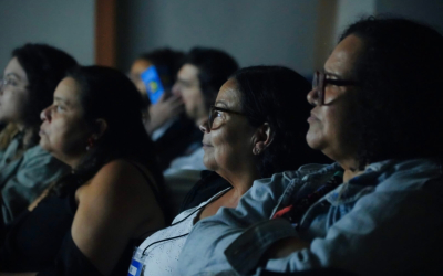 Rosto de pessoas em tela escura durante cinema