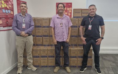 Imagem mostra três dirigentes sindicais em frente a dezenas de cestas básicas