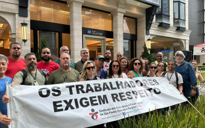Imagem mostra dirigentes do Sindicato dos Bancários em frente à porta do Banco Master, portanto uma faixa onde se lê "os trabalhadores exigem respeito"
