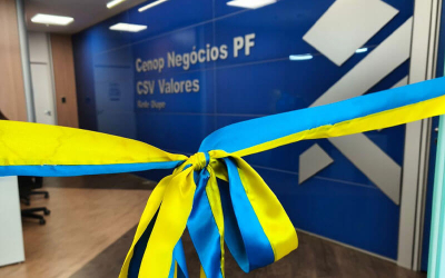 Imagem mostra uma fita de inauguração em frente a um saguão. A parede oposta à fita contém