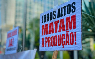 Imagem do ato contra a taxa selic, relizado pleos trabalhadores, mostra placa onde se lê "juros altos matam a  população"