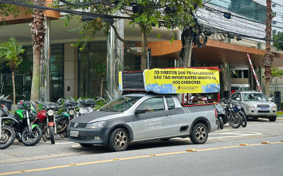 Imagem mostra um carro portando uma placa onde se lê "os direitos dos trabalhadores são tão importantes quanto os dos credores"