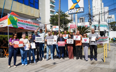 Imagem mostra trabalhadores protestando em frente a uma agência da Caixa