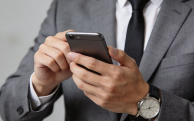 Imagem mostra um homem vestido de terno e gravata mexendo no telefone celular