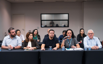 Foto dos representantes dos empregos da Caixa na mesa de negociação com o banco desta quarta (19); ao microfone, a diretora do Sindicato, Luiza Hansen