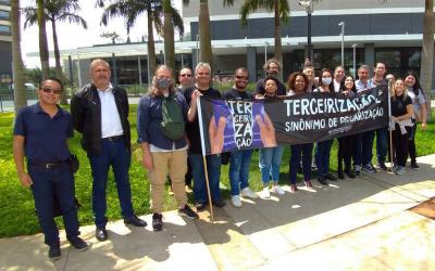 Imagem mostra dirigentes sindicais lado a lado segurando uma faixa onde se lê "terceirização: sinônimo de precarização". A foto foi tirada durante protesto contra terceirização no Santander, em frente ao Conexão Santander