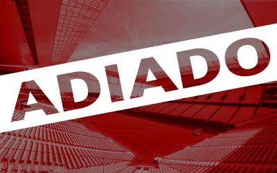 Arte com a foto do estádio vazio do Corinthians ao fundo, sob um filtro vermelho, sobreposto a palavra "adiado"