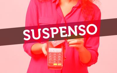 Uma faixa com a palavra "suspenso" em frente uma mulher segura uma maquina de débito e crédito Getnet