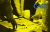 Imagem mostra pessoas debruçadas sobre uma mesa com vários papeis sobre ela. No canto superior direito está posicionado o logo da Cassi. A imagem tem um filtro amarelo 