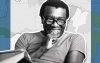 Imagem de Milton Santos, um homem negro, de óculos, sorrindo, na faixa dos 50 a 60 anos.