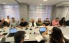 Imagem mostra representantes dos trabalhadores reunidos com representantes do banco, dentro de uma sela e sentados frente a frente em um mesa branca e comprida