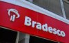 Imagem mostra detalhe da fachada de uma agência do Bradesco. A Imagem mostra o logo do banco ao lado da palavra "Bradesco"