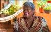 Imagem mostra Sonia Estela, a Fumaça. Ela é uma mulher negra, de cabelos curtos e grisalhos, com 63 anos de idade. Usa uma roupa marrom bordada com motivos africanos. 