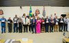 Imagem mostra personagens que fizeram a greve de 1985. Eles estão lado a lado na sala da assembleia legislativa de são paulo e seguram placas de homenagem