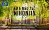 Divulgação do filme "Eu e meu avô Nihonjin" com uma arte que mostra uo protagonista Noboru e seu avô Hideo conversando em uma área arborizada no meio de uma cidade.
