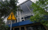 Imagem mostra fachada do prédio são joaquim da caixa econômica federal. em frente ao prédio há uma placa com um ponto de exclamação dentro de um triângulo amarelo com linhas negras seguindo paralelamente os lados da figura geométrica. a placa é o sinal universal para indicar perigo