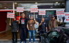 imagem mostra dirigentes perfiladas portando placas em frente a uma agência do Santander durante protesto 