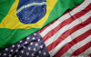 Imagem divida ao meio, na diagonal, do canto supeior direito ao canto inferior esquerdo. Na parte de cima, há a bandeira do Brasil. Na parte de baixo há bandeira dos Estados Unidos