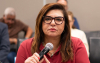 Foto da presidenta do Sindicato dos Bancários de São Paulo, Neiva Ribeiro, com uma camisa vermelho, segurando o microfone, na mesa de negociação com a Fenaban