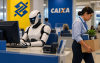 Imagem feita por inteligência artificial mostra um robô sentado em frente a um computador enquanto uma mulher vai embora de cabeça baixa segurando uma caixa com pertences. Ao fundo dois banneres, um amarelo com o logo do banco do brasil e outro azul com o logo da caixa econômica federal