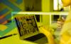 Arte com filtro amarelo composta por uma pessoa em frente a um notebook, em uma reunião virtual. A arte tem um filtro amarela e é integrada ao logo do Banco do Brasil