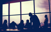 Imagem mostra silhuetas de pessoas em volta de uma mesa e em frente a uma janela grande