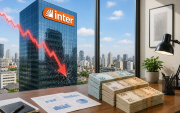 Imagem mostra uma pillha de dinheiro sobre uma mesa em uma sala com uma janela com vista para um prédio com um letreiro do Banco Inter. sobre o prédio há um gráfico em linha na cor vermelha indicando queda
